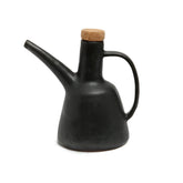 Black ceramic oil dispenser with a cork lid on a white background