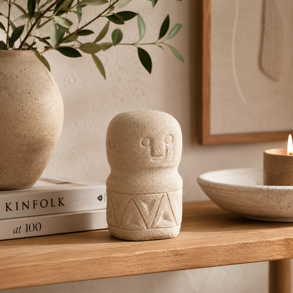 Decorative stone figure on a wooden surface with books and a candle in the background