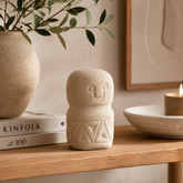Decorative stone figure on a wooden surface with books and a candle in the background