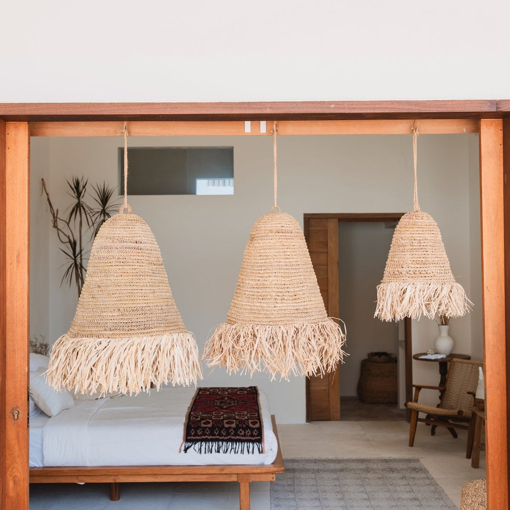 Three woven pendant lights hanging in a room with a bed and decor.