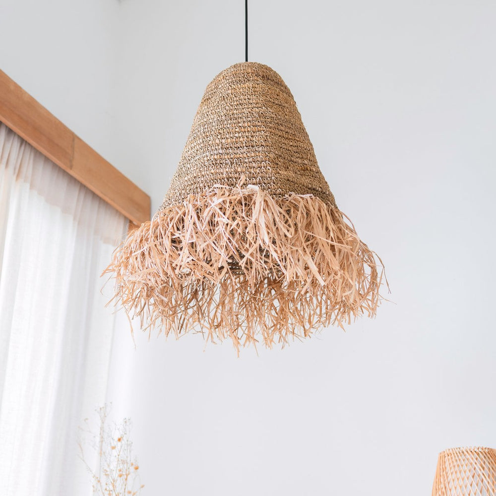 Woven pendant light with natural fibers hanging against a white wall.